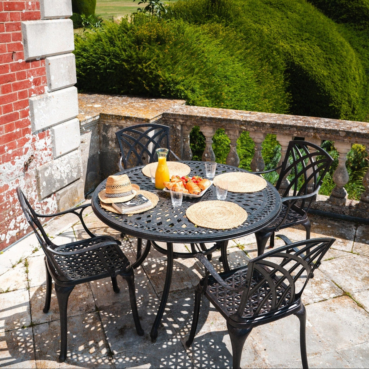 Outdoor dining setup on a balcony with a scenic view of greenery and fields.