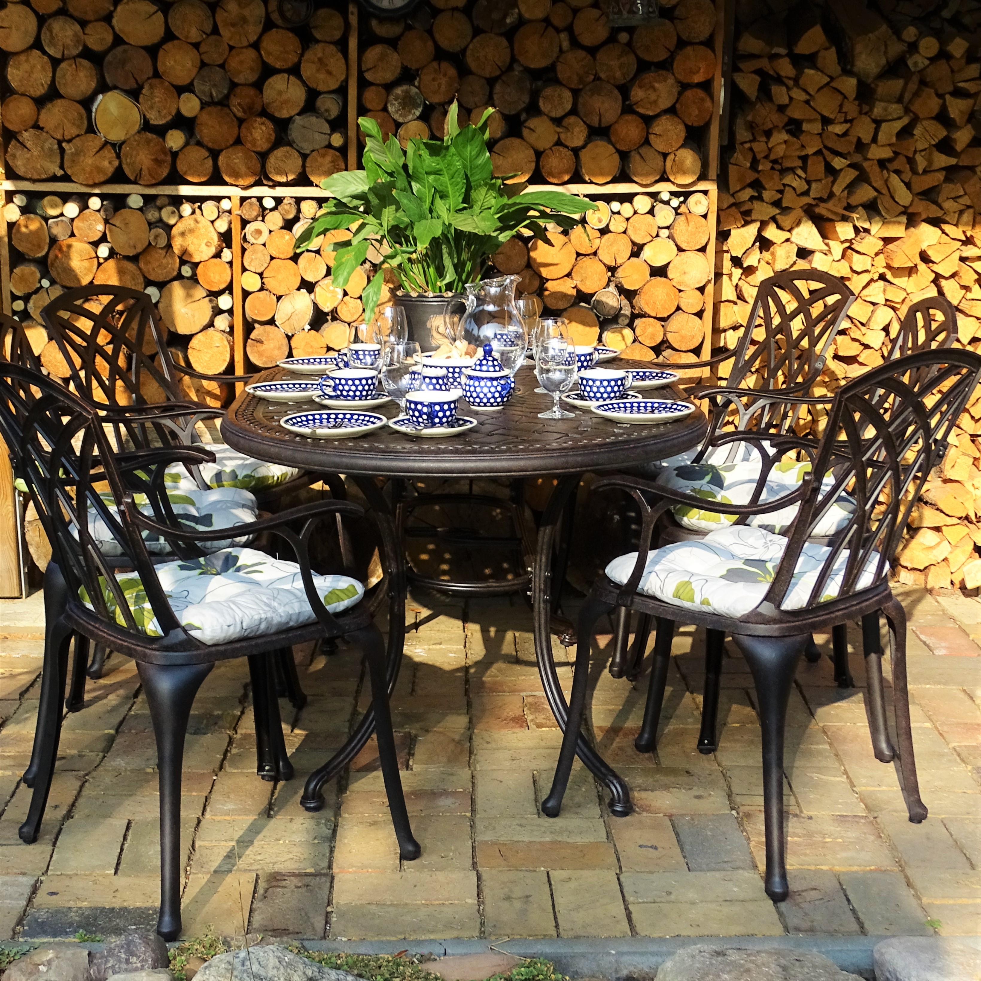 Gartentisch auf Terrasse mit Sitzkissen, blauem Gedeck und Blumenvasendekoration