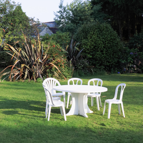 Weißes Gartenmöbel-Set aus Kunststoff mit Tischdecke auf der Terrasse von Pflanzen umringt